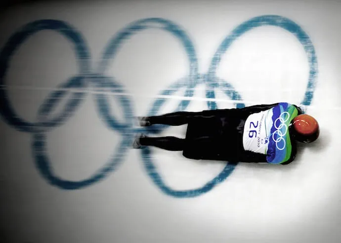 Ander Mirambell baja de cabeza con el dorsal 26 sobre los aros olímpicos pintados en el muro de la pista de Vancouver 2010
